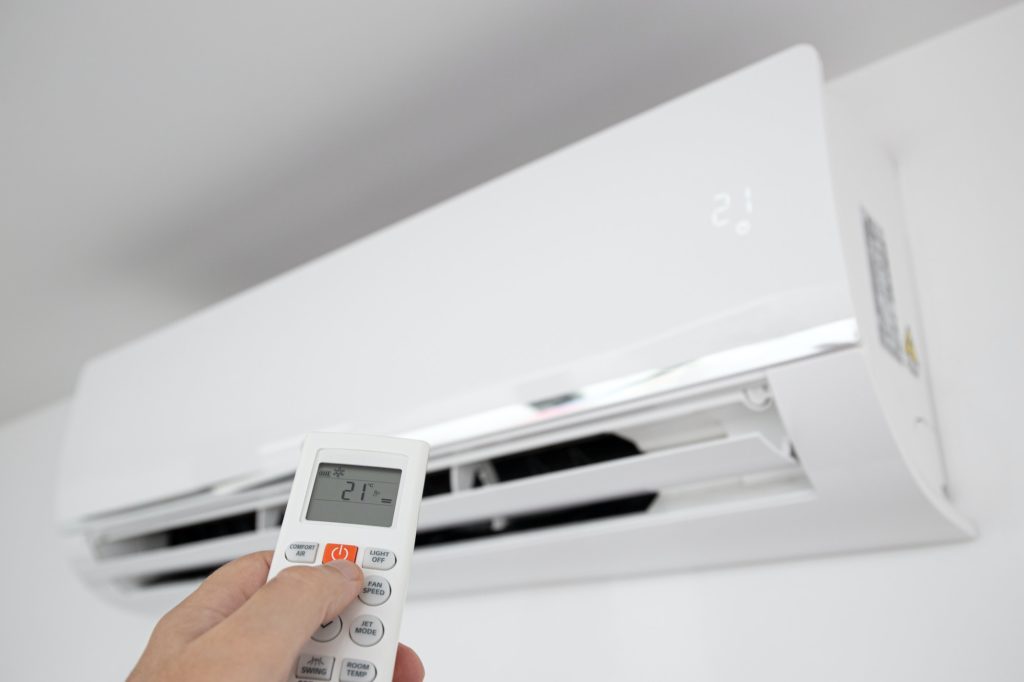 aHand operating a Remote control of a Domestic Air conditioner unit