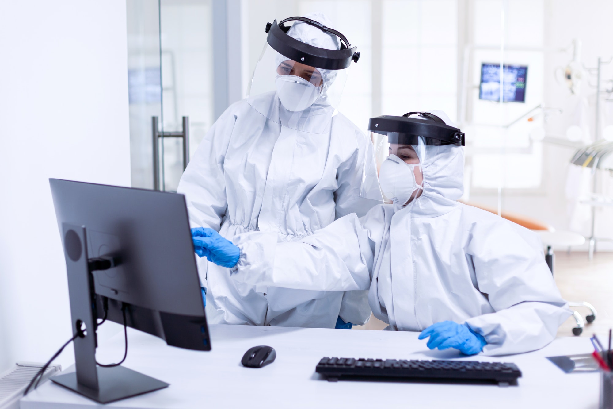 Doctor and nurse in ppe suit looking at monitor